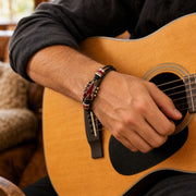 Red guitar bracelet worn while strumming an acoustic guitar