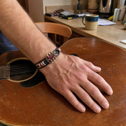Red guitar bracelet on a man's wrist resting on his guitar