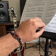 Red guitar bracelet worn while turning sheet music