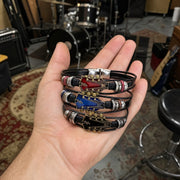 Three guitar bracelets, red, blue and black, in one hand