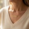 Custom Name Necklace - woman wearing gold name pendant with cashmere sweater